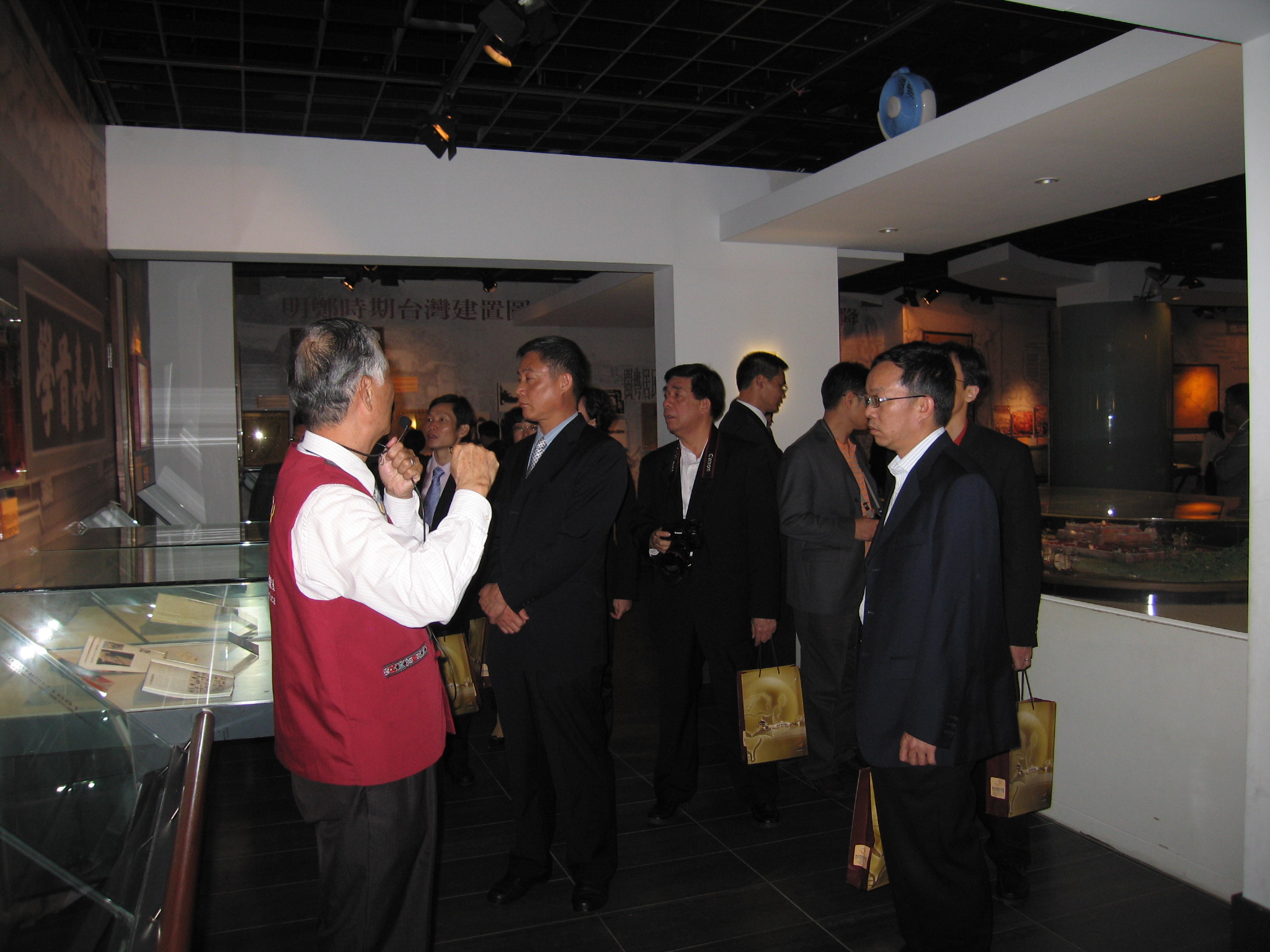 本館志工隊張總幹事慶龍(左1)為參訪來賓作展場導覽