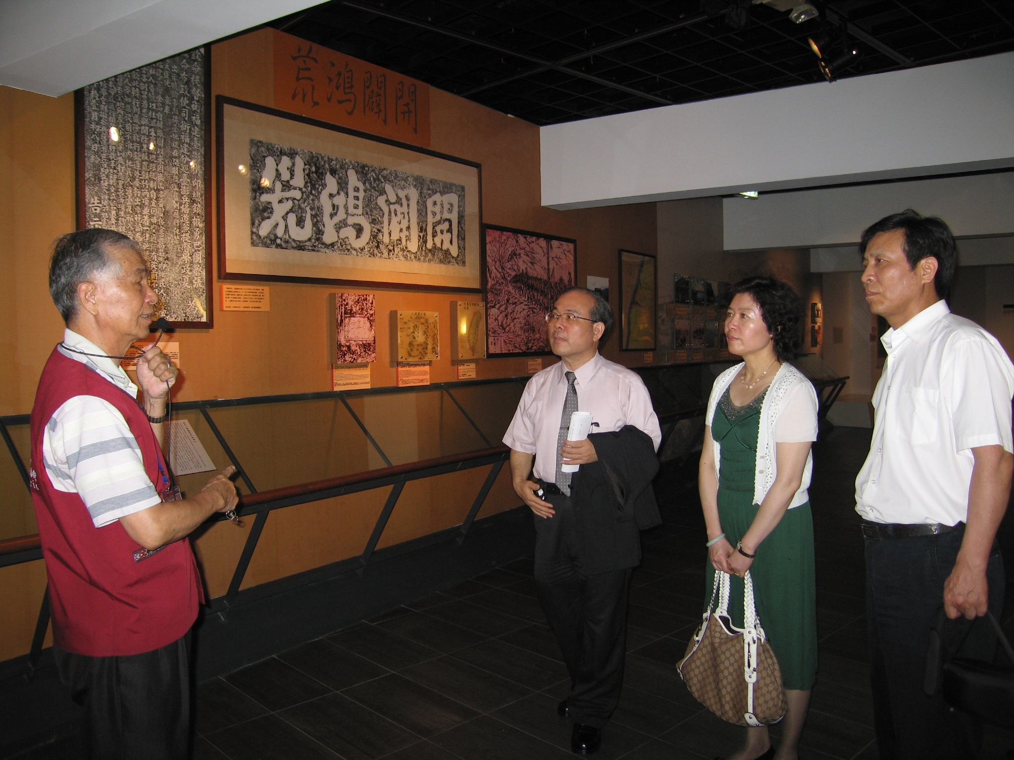 志工張總幹事慶龍(左)為參訪來賓導覽本館展示史料