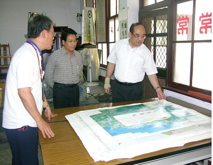 孫振明先生（左）向本館張館長鴻銘（右）與整理組林組長明洲（中）展示所蒐藏之早期鄉鎮行政區域圖