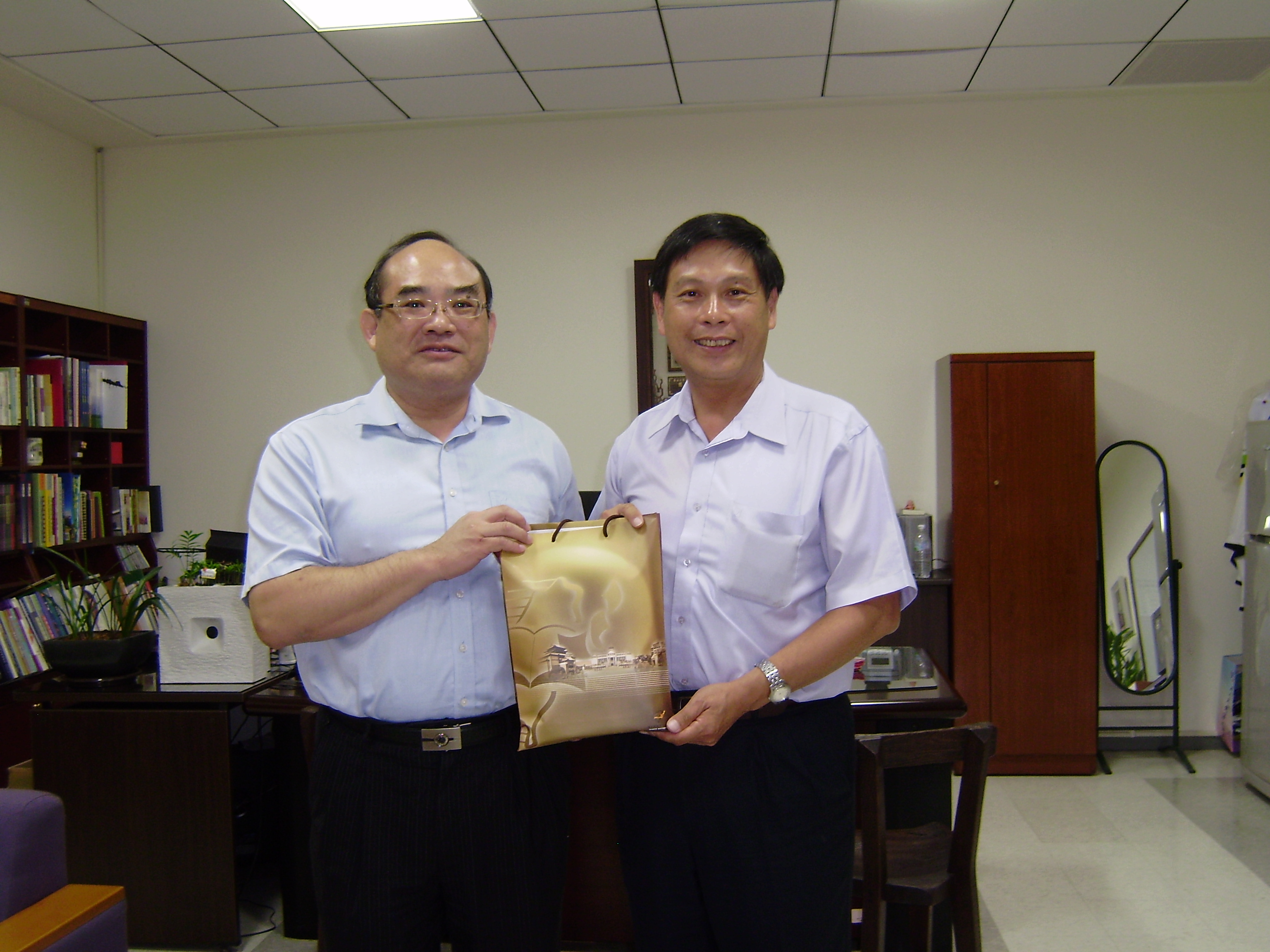 張鴻銘館長（左）致贈新竹縣政府文化局蔡榮光局長（右）宣導品